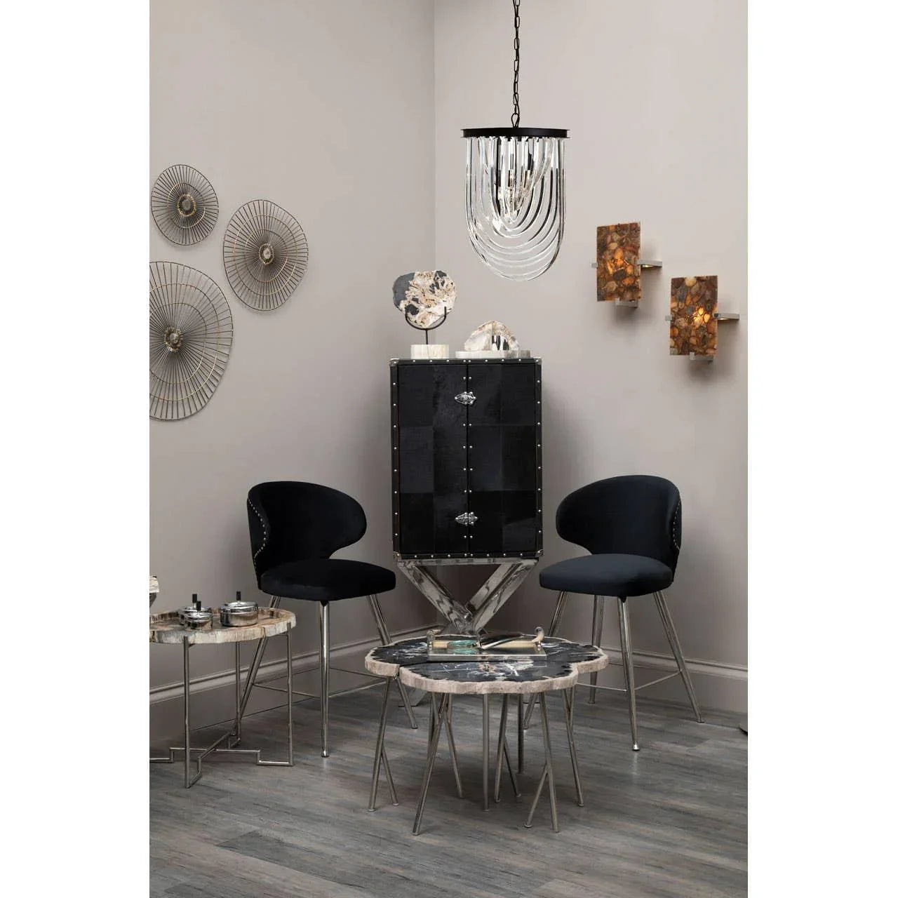 Modern black bar cabinet with metal legs, two black accent chairs and marble side tables