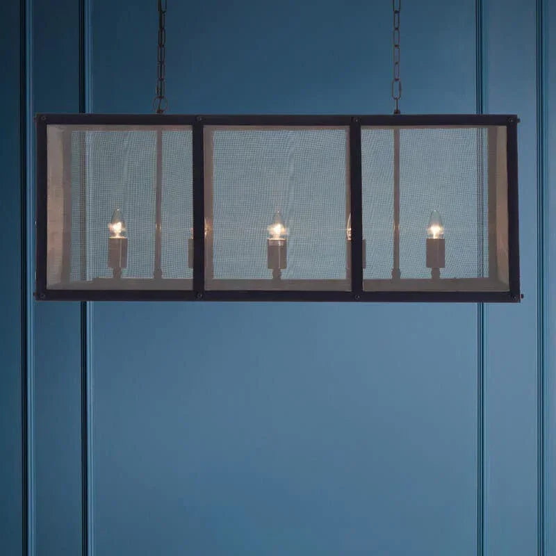 Rectangular industrial pendant light with mesh shade and exposed bulbs against blue wall