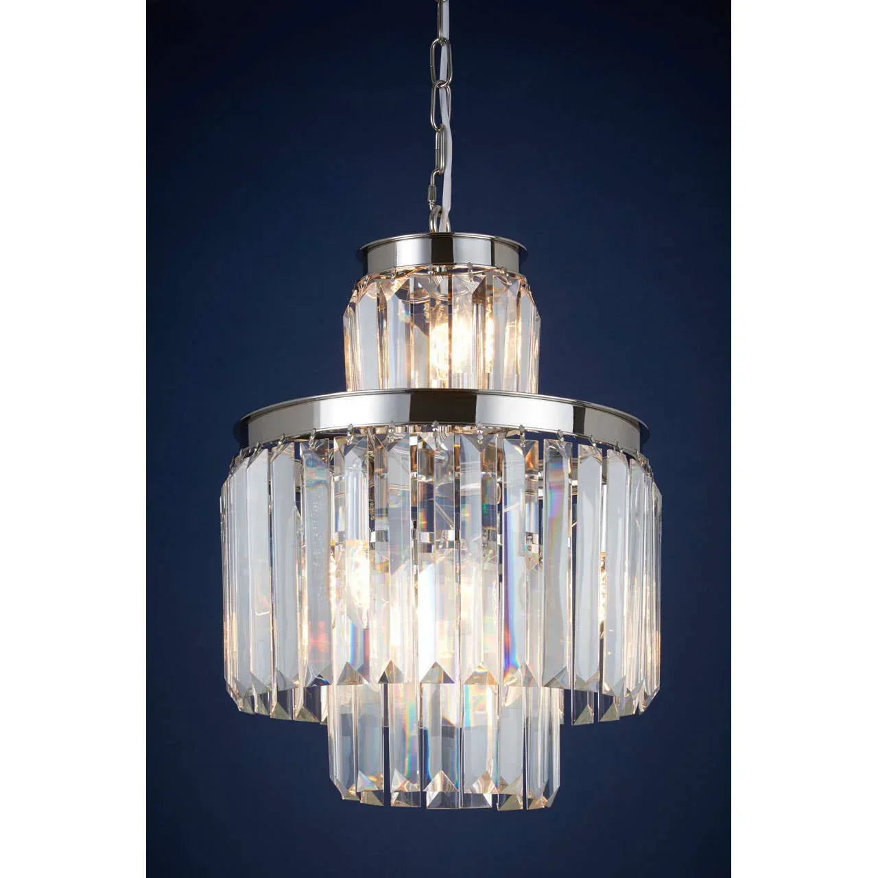 Chrome and crystal pendant light with tiered glass prisms against dark blue background