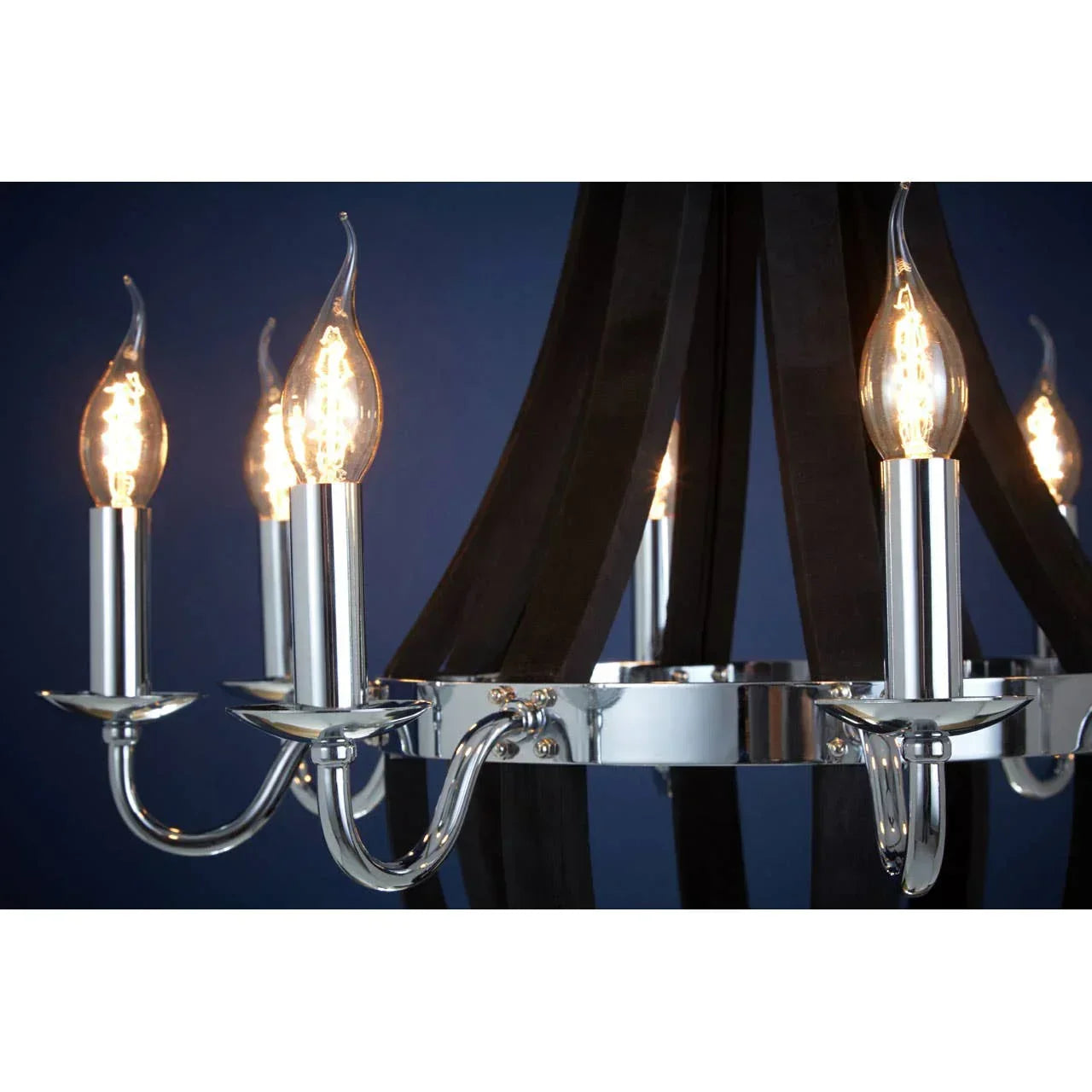 Chrome chandelier with candle-style light bulbs and black curved arms against blue wall