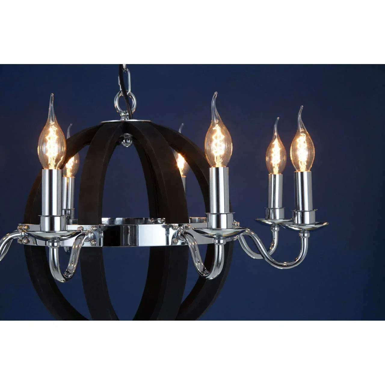 Chrome and black chandelier with six candle-style lights against a dark blue wall