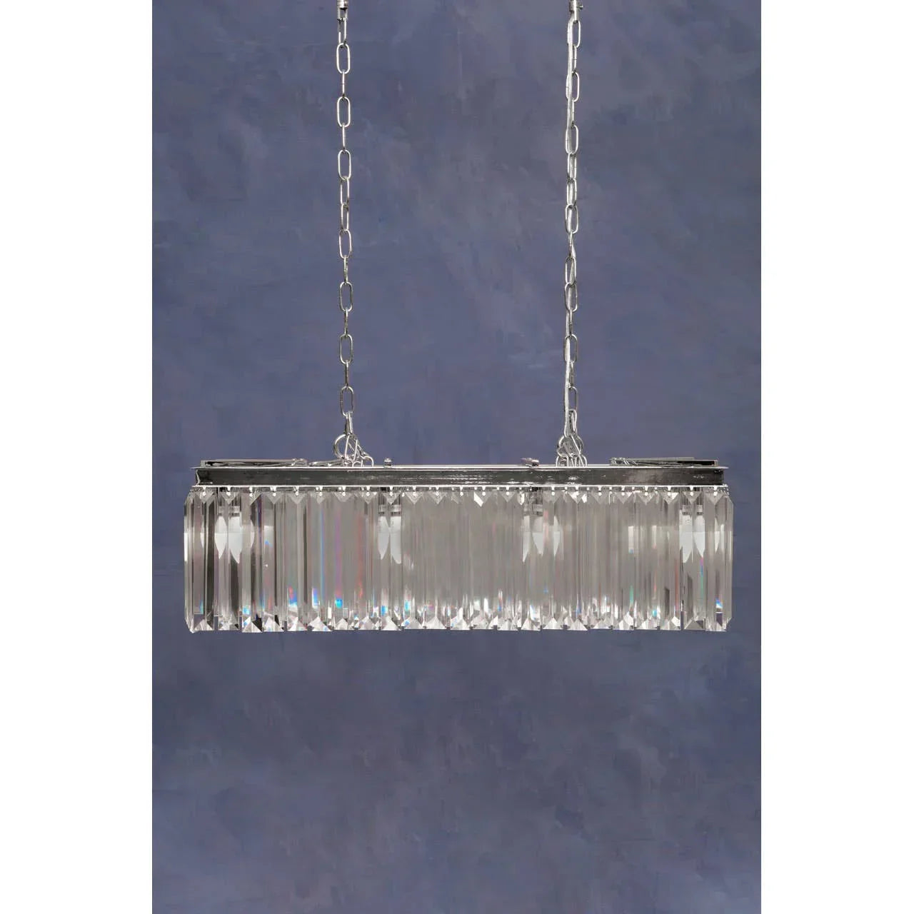 Rectangular crystal chandelier with chrome frame and hanging chains against blue wall