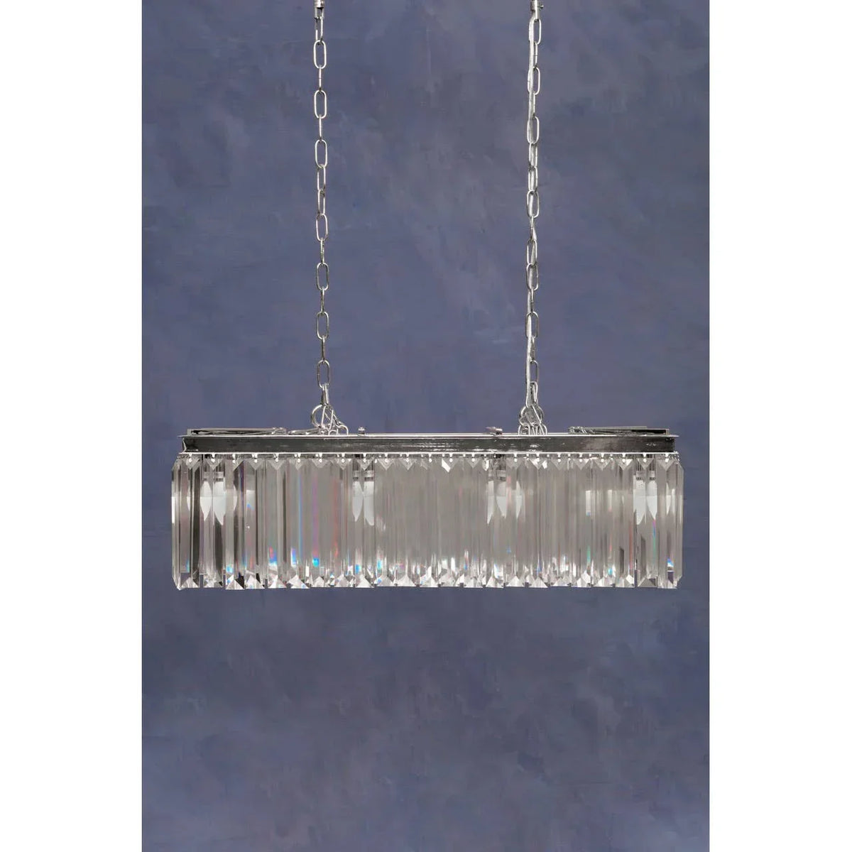 Rectangular crystal chandelier with chrome frame and hanging chains against blue wall