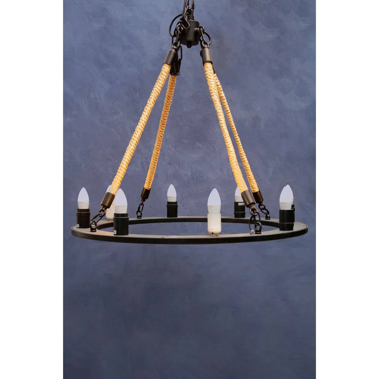 Black round chandelier with rope accents and six candle-style bulb holders against blue wall