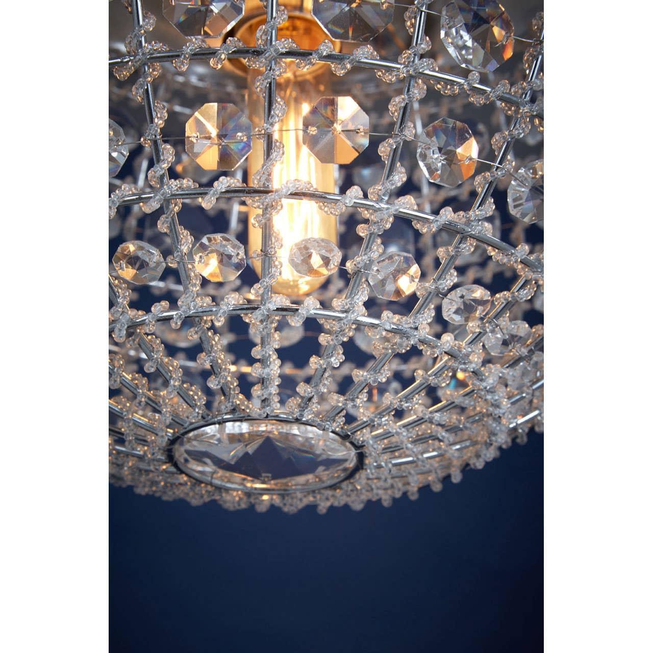Crystal ceiling light with decorative metal lattice and exposed bulb against dark blue background