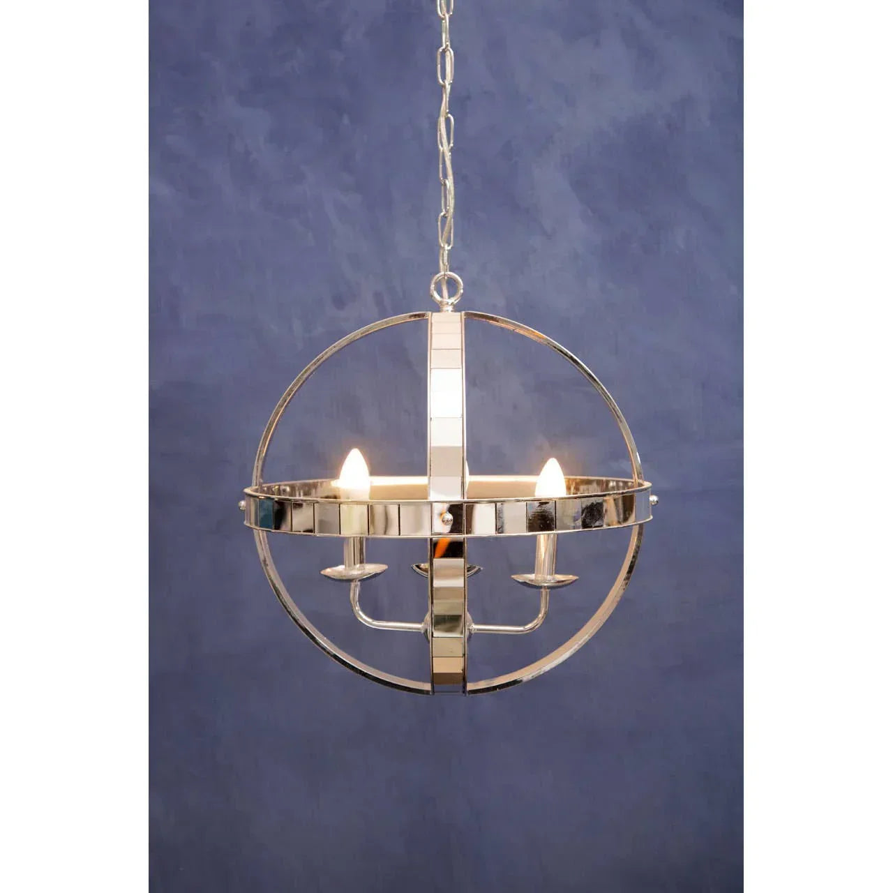 Chrome spherical pendant light with two candles against a blue textured wall