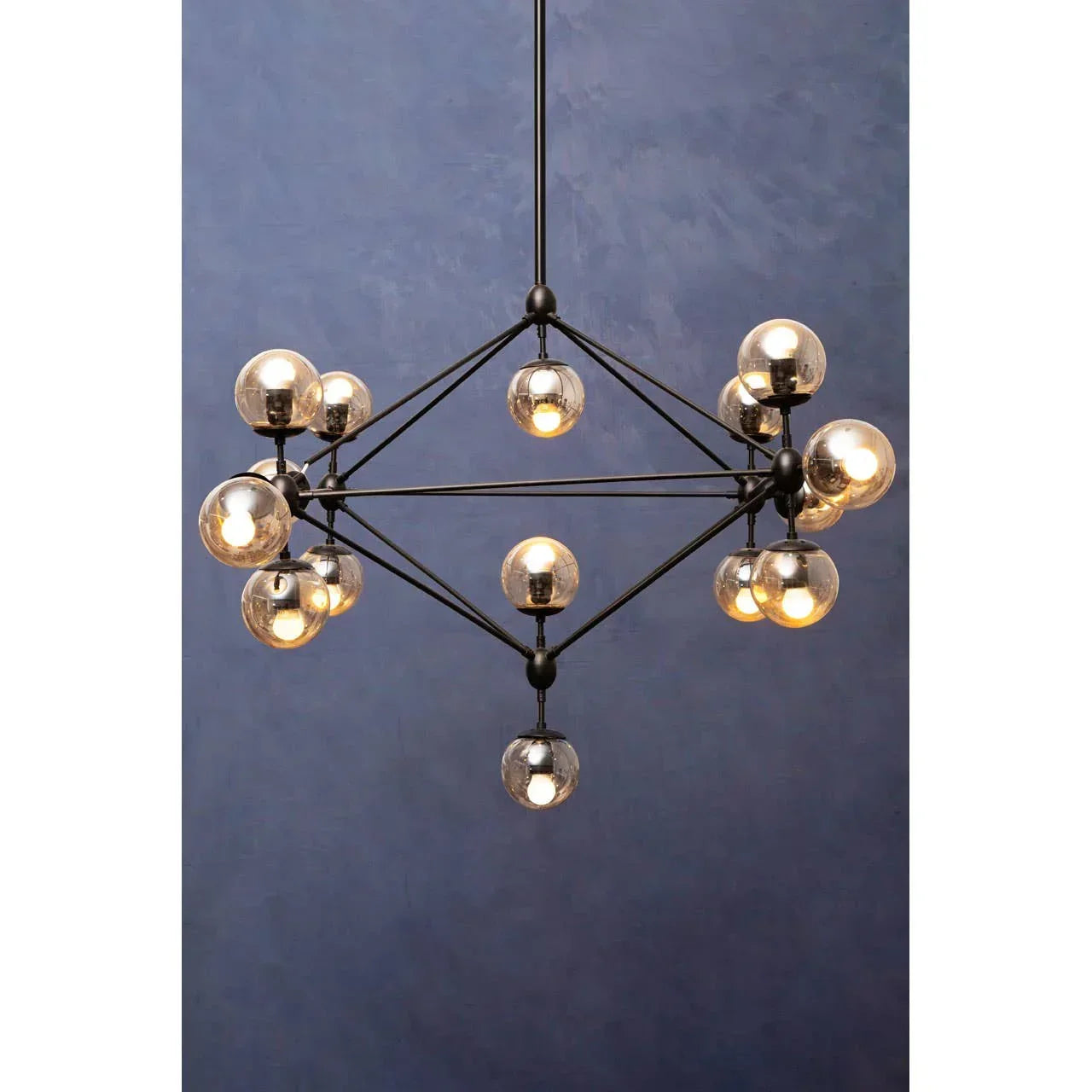 Black metal chandelier with glass globe lights against blue wall