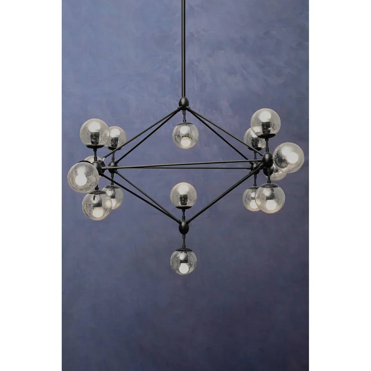 Modern black chandelier with glass globe lights against a blue wall