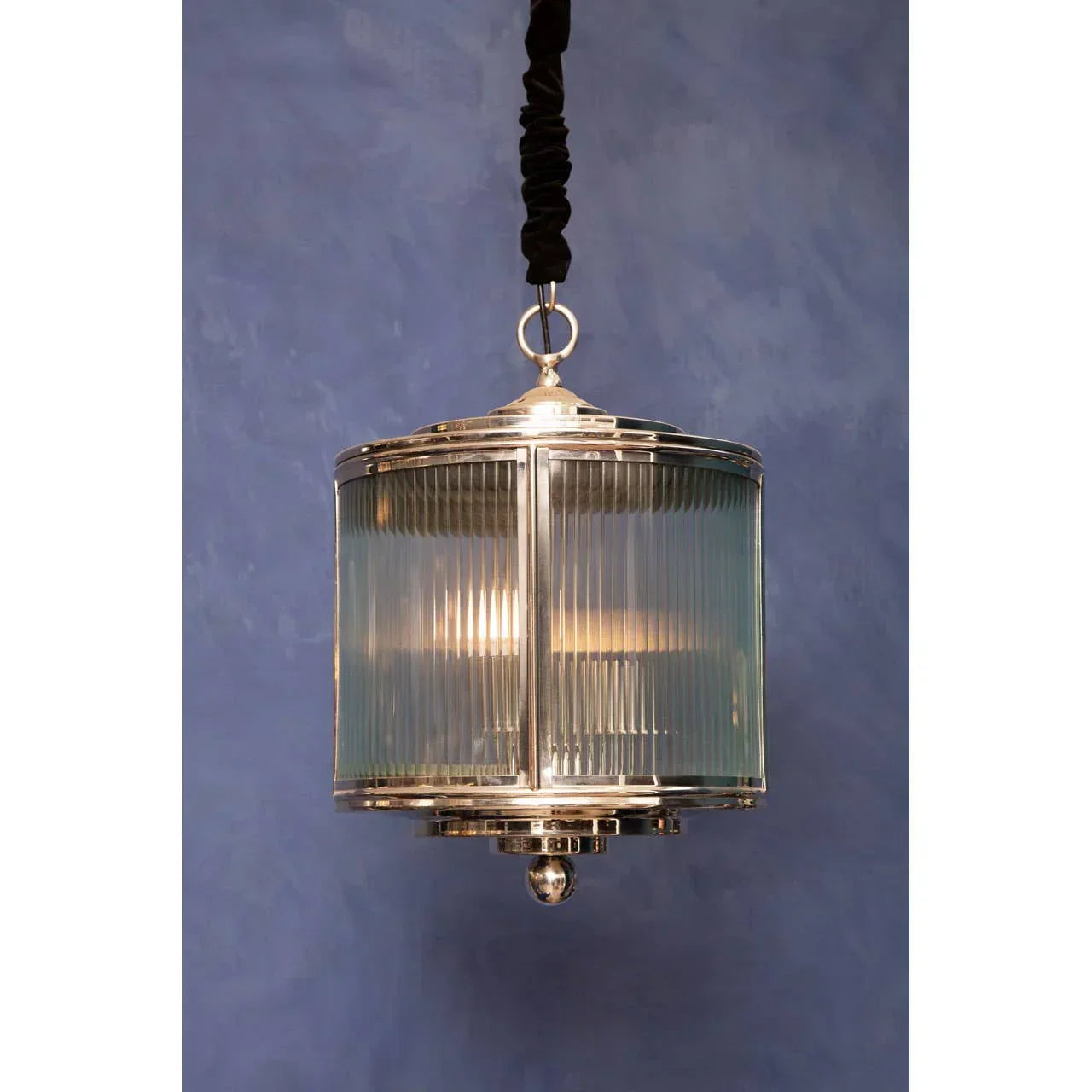 Glass and chrome pendant light with ribbed detail against blue wall
