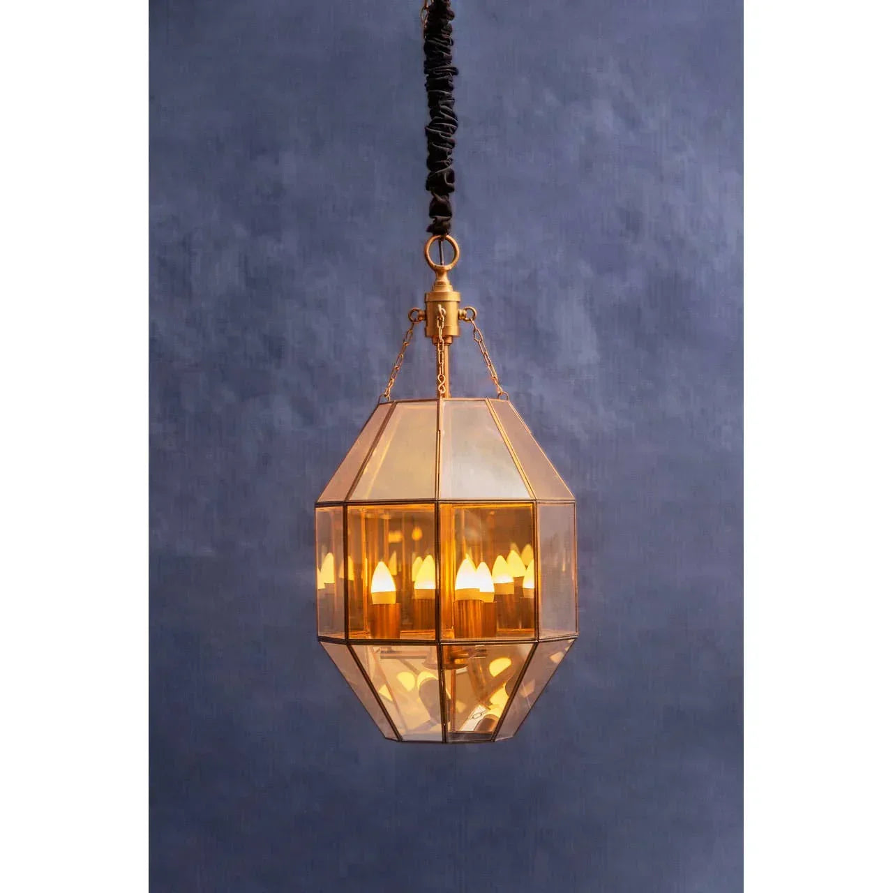 Geometric gold glass pendant ceiling light with candle-style bulbs against blue wall