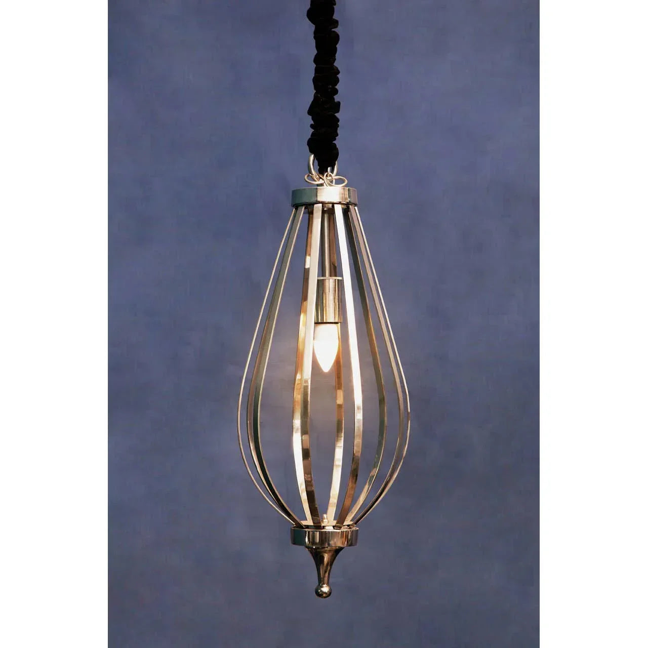 Gold metal pendant light with open cage design and exposed bulb against blue wall