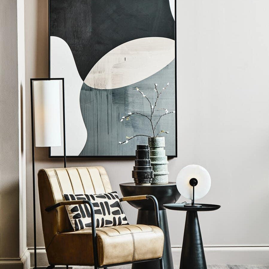 Tan leather accent chair with black frame, geometric pillow, and side tables in modern living room