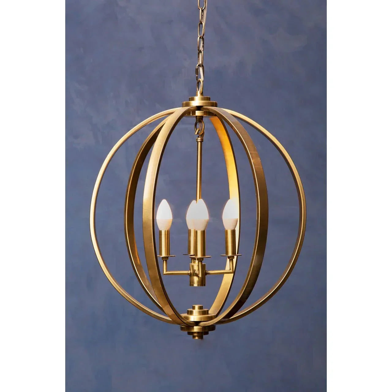 Gold metal orb chandelier with four candle-style lights and chain hanging against blue wall