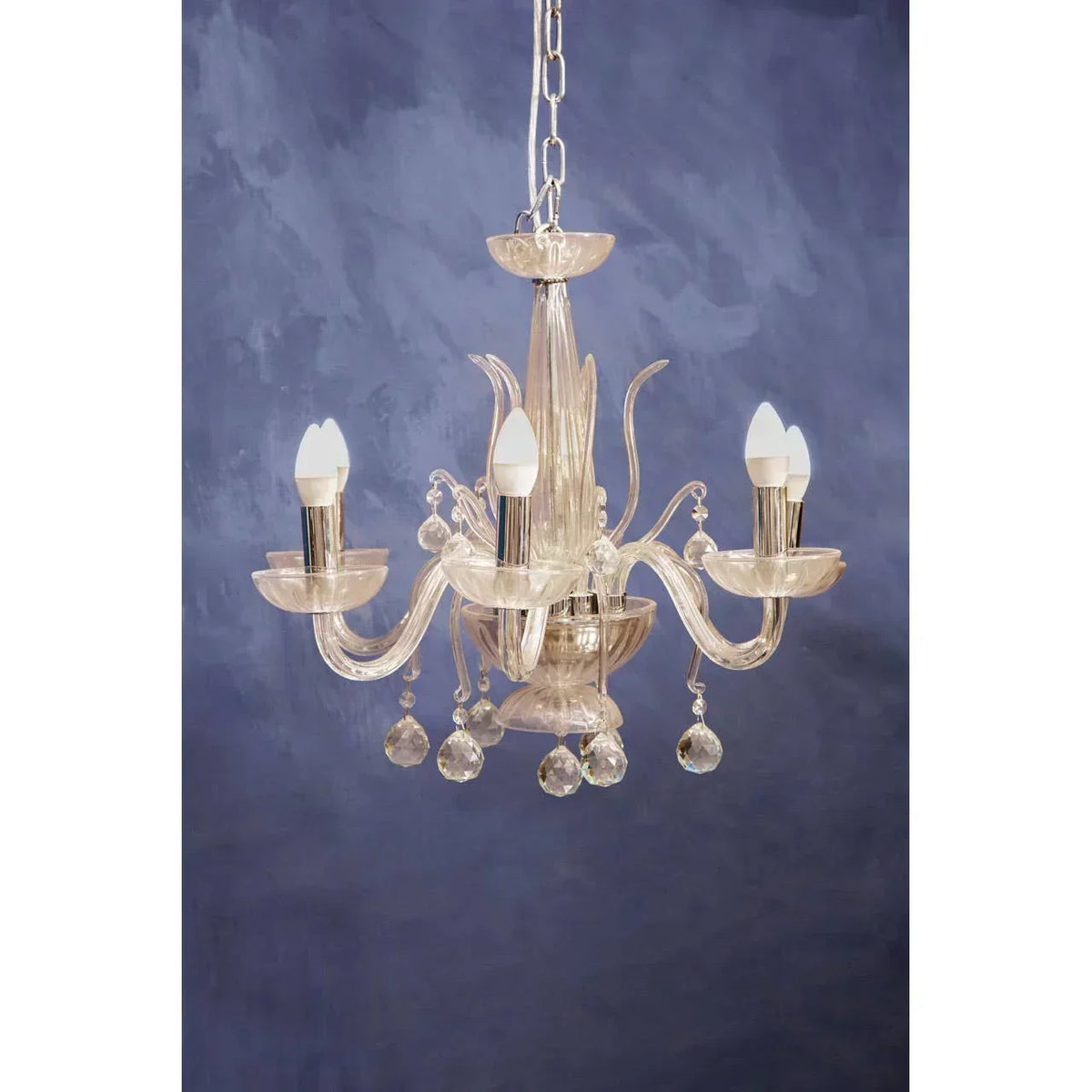 Glass chandelier with curved arms and crystal pendant lights against blue wall