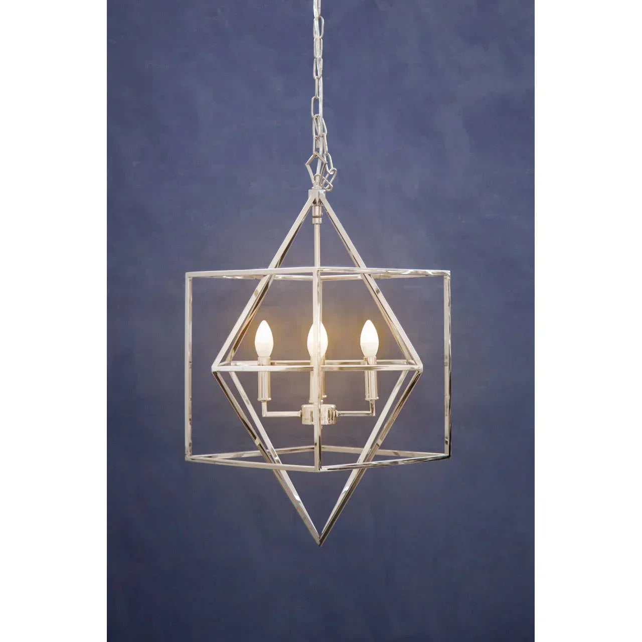 Modern geometric chrome pendant light with three bulbs against a blue wall