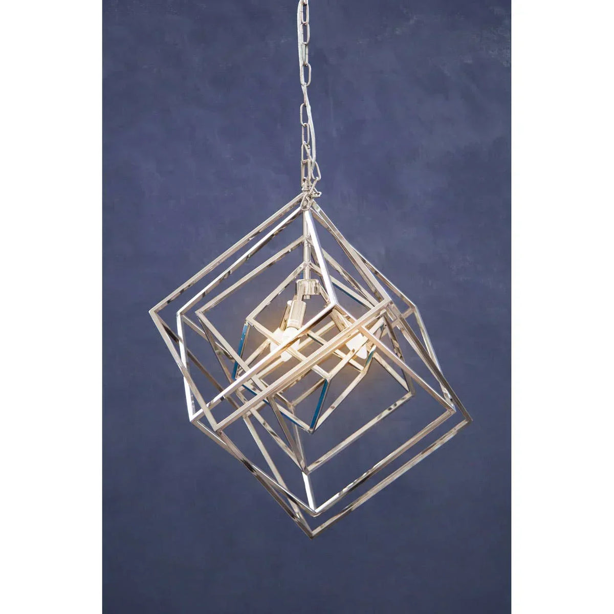 Geometric chrome pendant light with open metal cube frames and visible bulb against navy wall