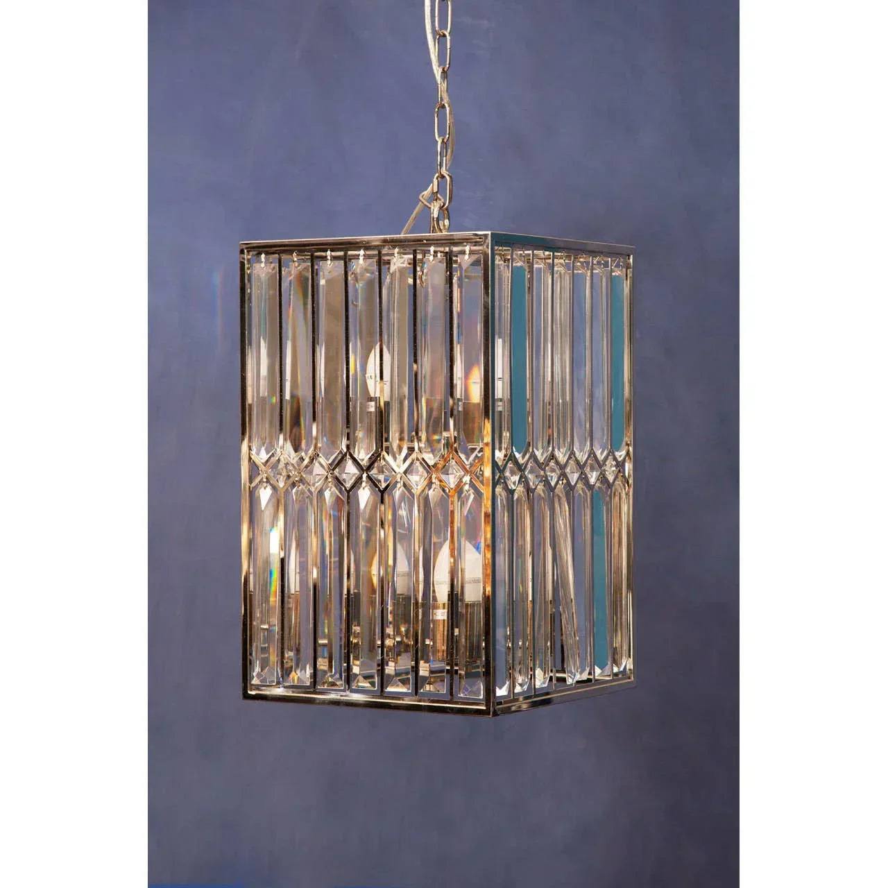 Rectangular crystal pendant light with gold frame and hanging chain against blue wall