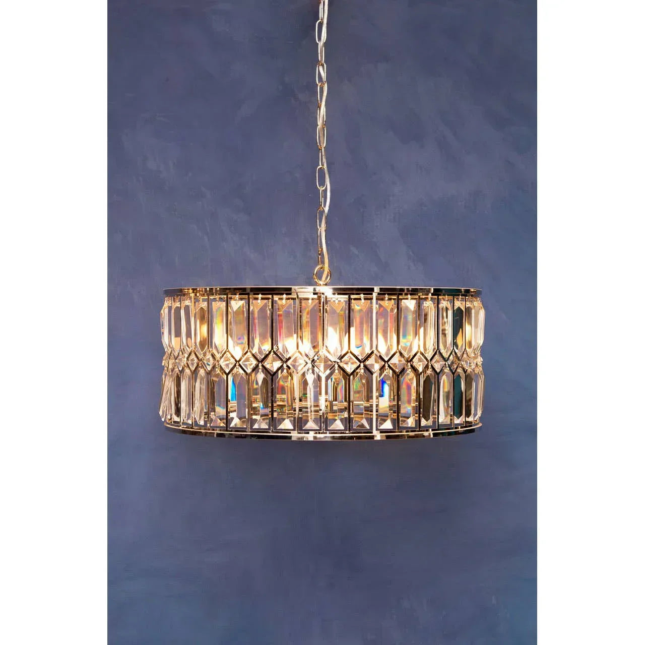 Gold crystal ceiling light pendant with circular frame against blue wall
