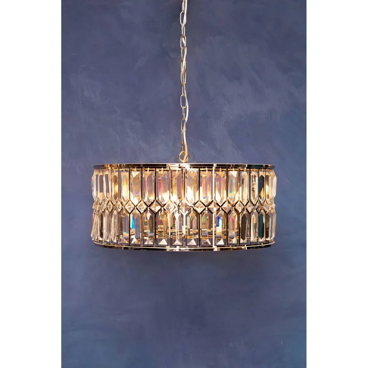 Gold crystal ceiling light pendant with circular frame against blue wall