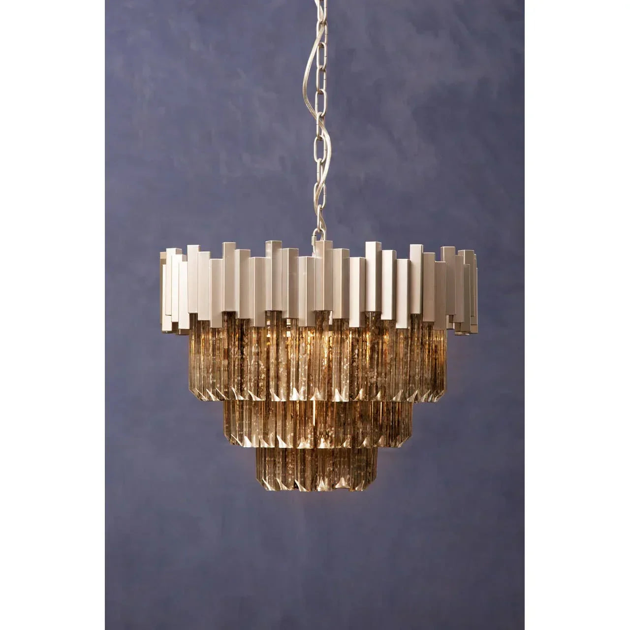 Tiered crystal chandelier with metal frame and gold glass pendants against blue wall