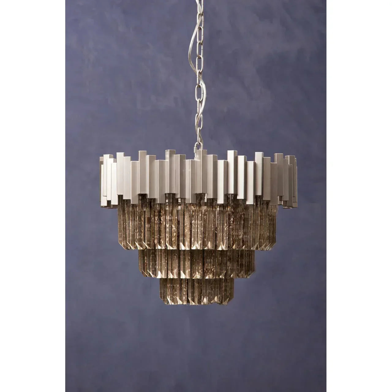 Modern tiered chandelier with silver metal frame and glass prisms against blue wall