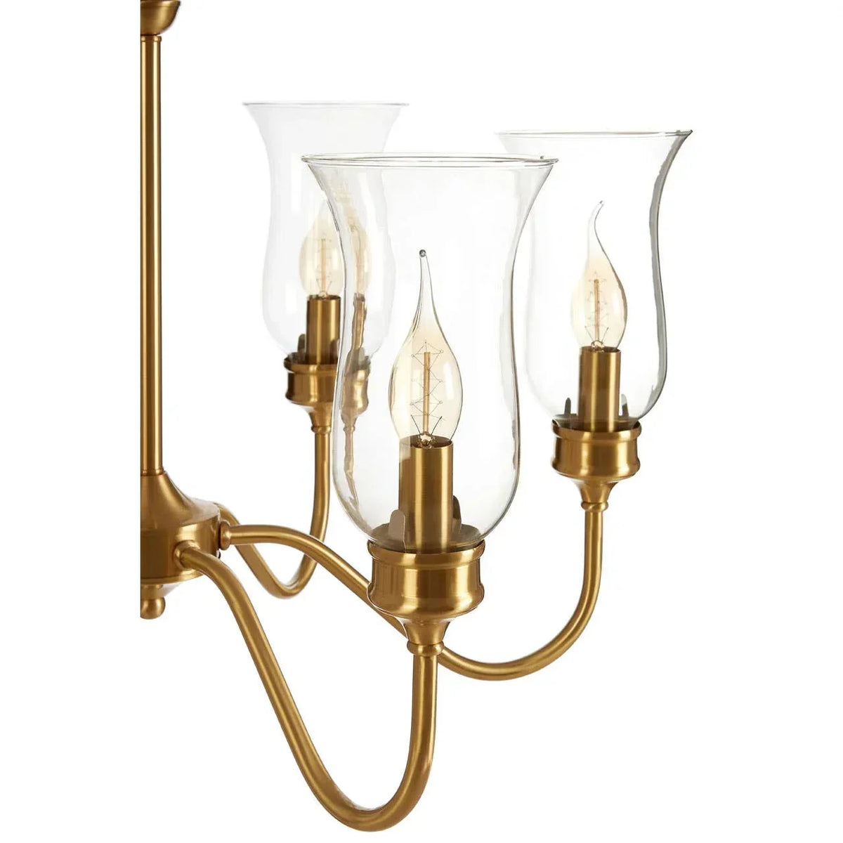 Brass chandelier with glass hurricane shades and exposed bulb detail
