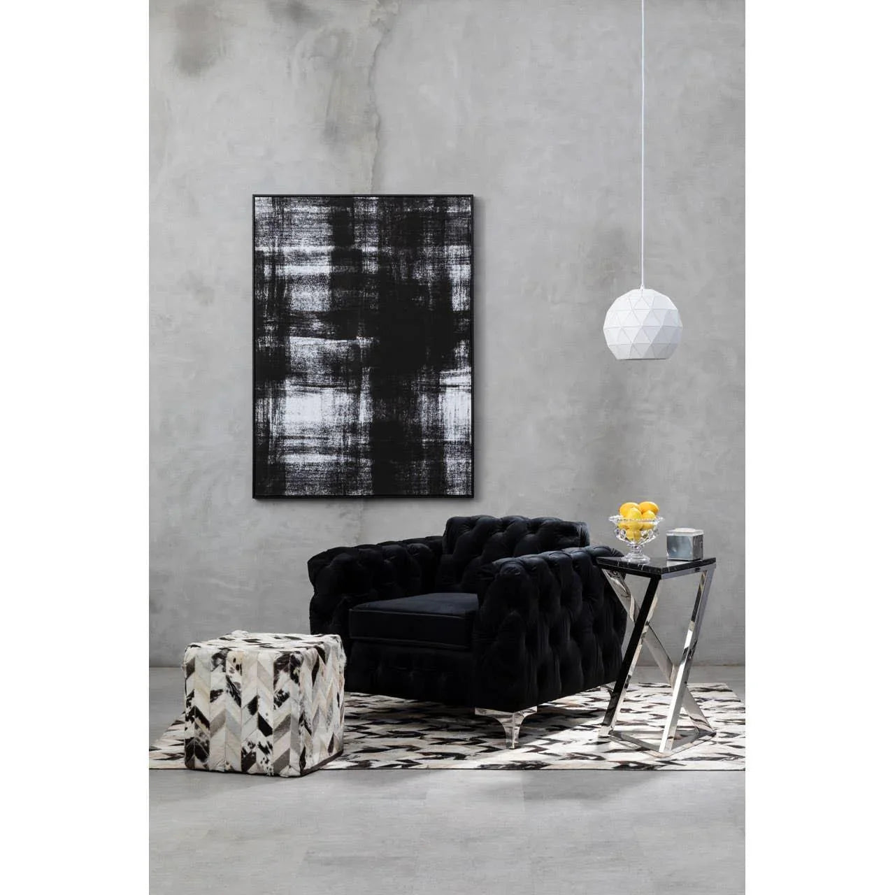 Black velvet armchair with chrome side table, geometric pouffe, and monochrome rug