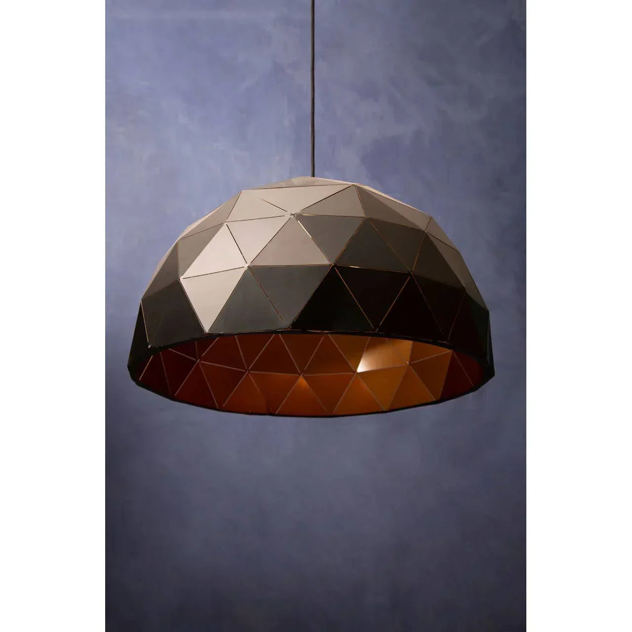 Geometric pendant light with black and copper metal shade against blue wall