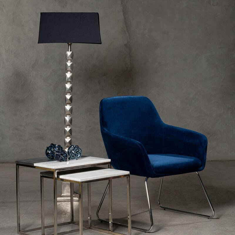 Velvet blue accent chair with modern nesting tables and metallic table lamp