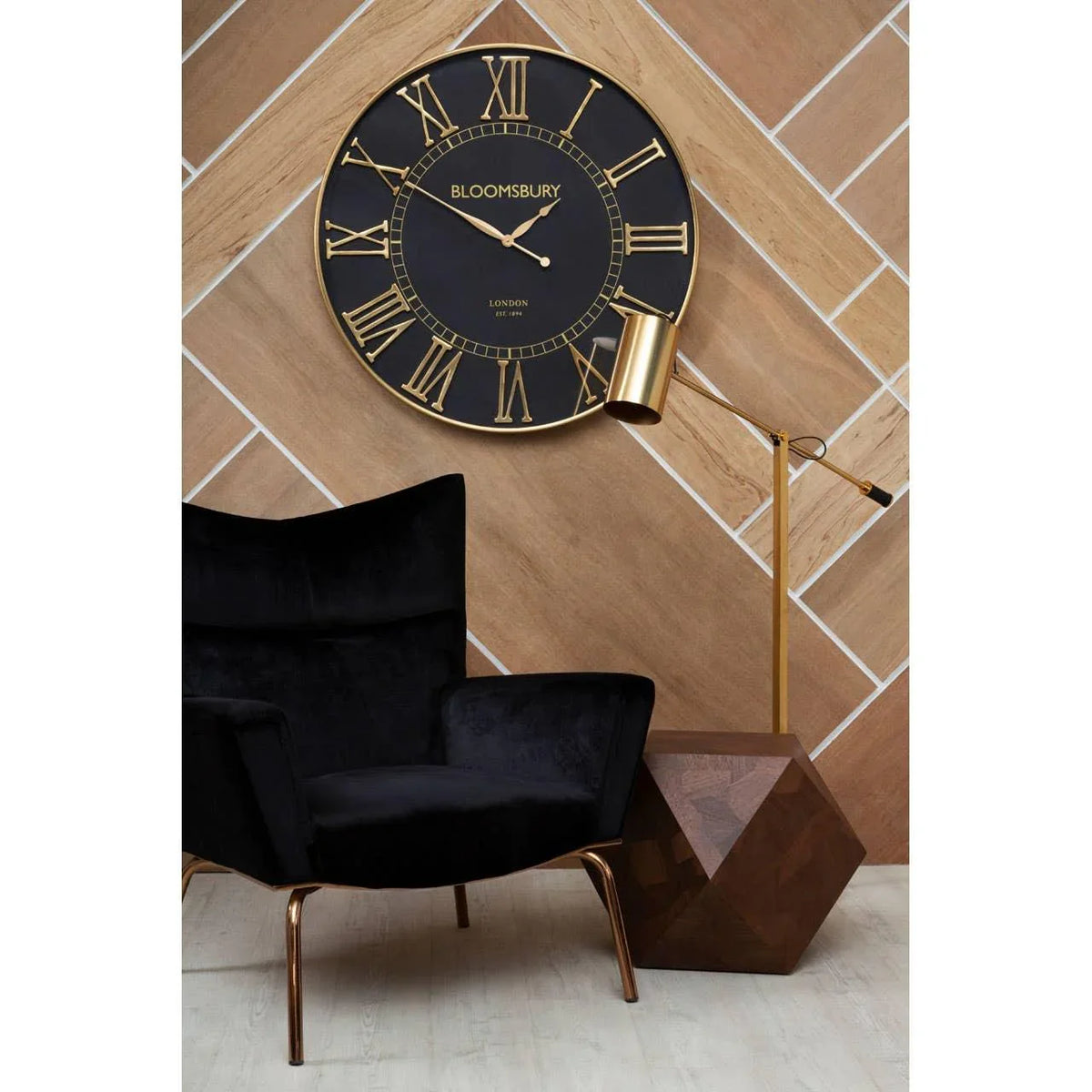 Black velvet accent chair with gold legs beside geometric wood side table and floor lamp