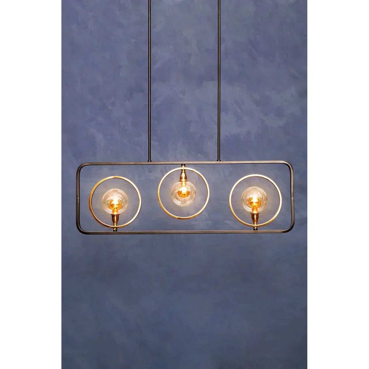 Modern pendant light with three exposed bulbs in gold rings on a rectangular black frame