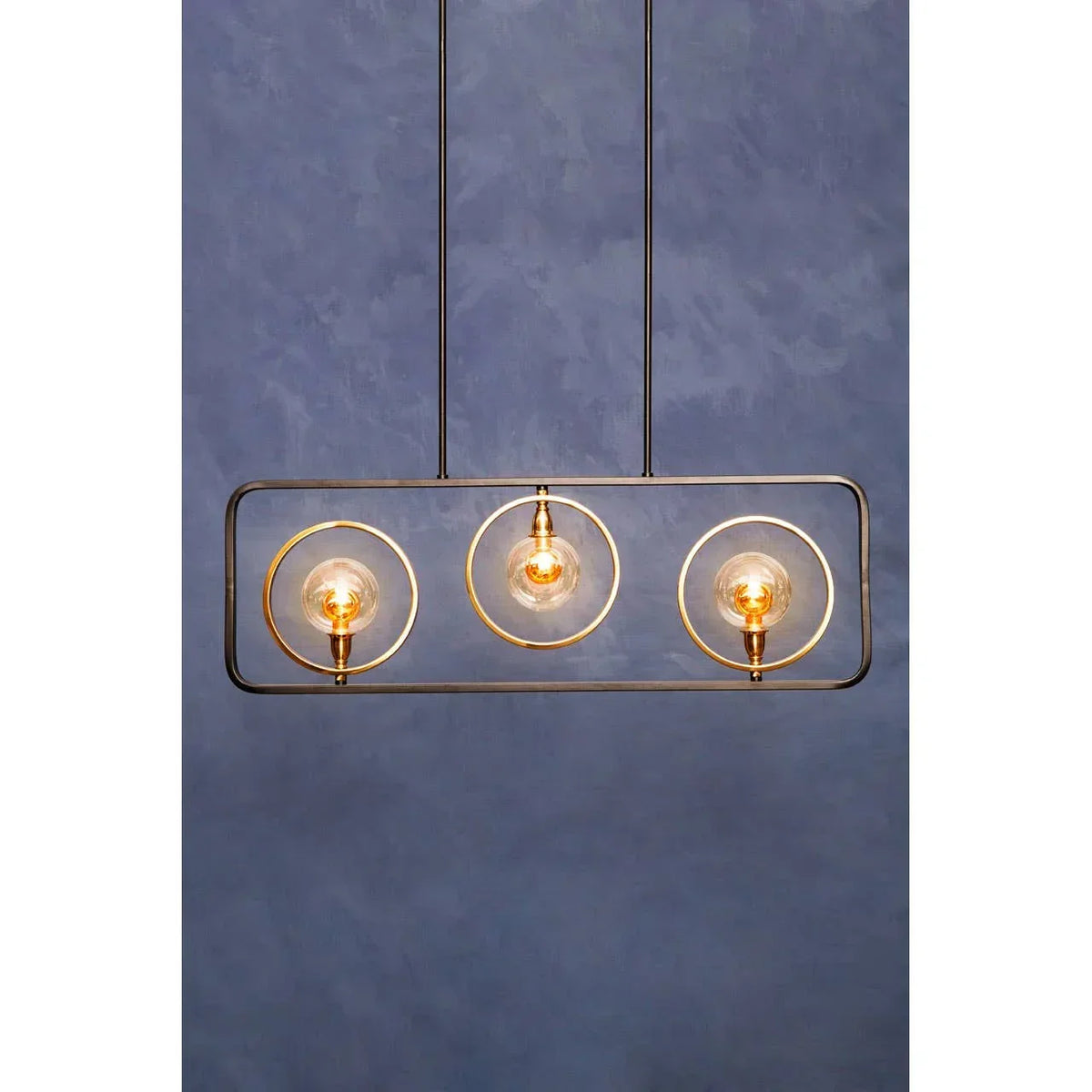 Modern pendant light with three exposed bulbs in gold rings on a rectangular black frame