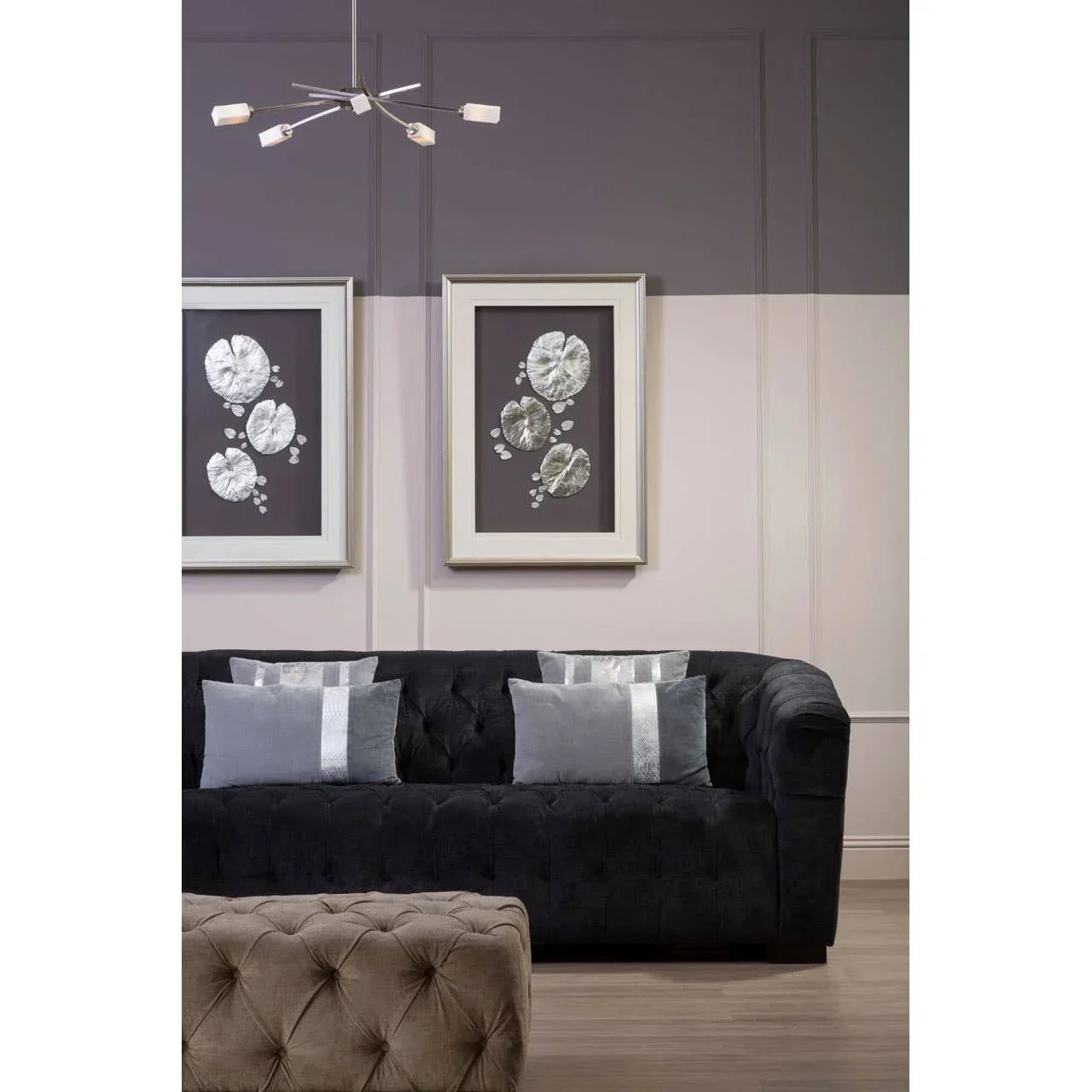 Black tufted velvet sofa with silver accent cushions in modern living room setting