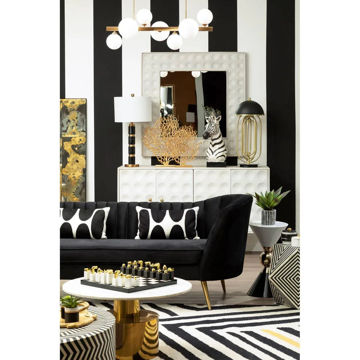 Black velvet sofa with monochrome scatter cushions, modern coffee table, striped rug, gold accents