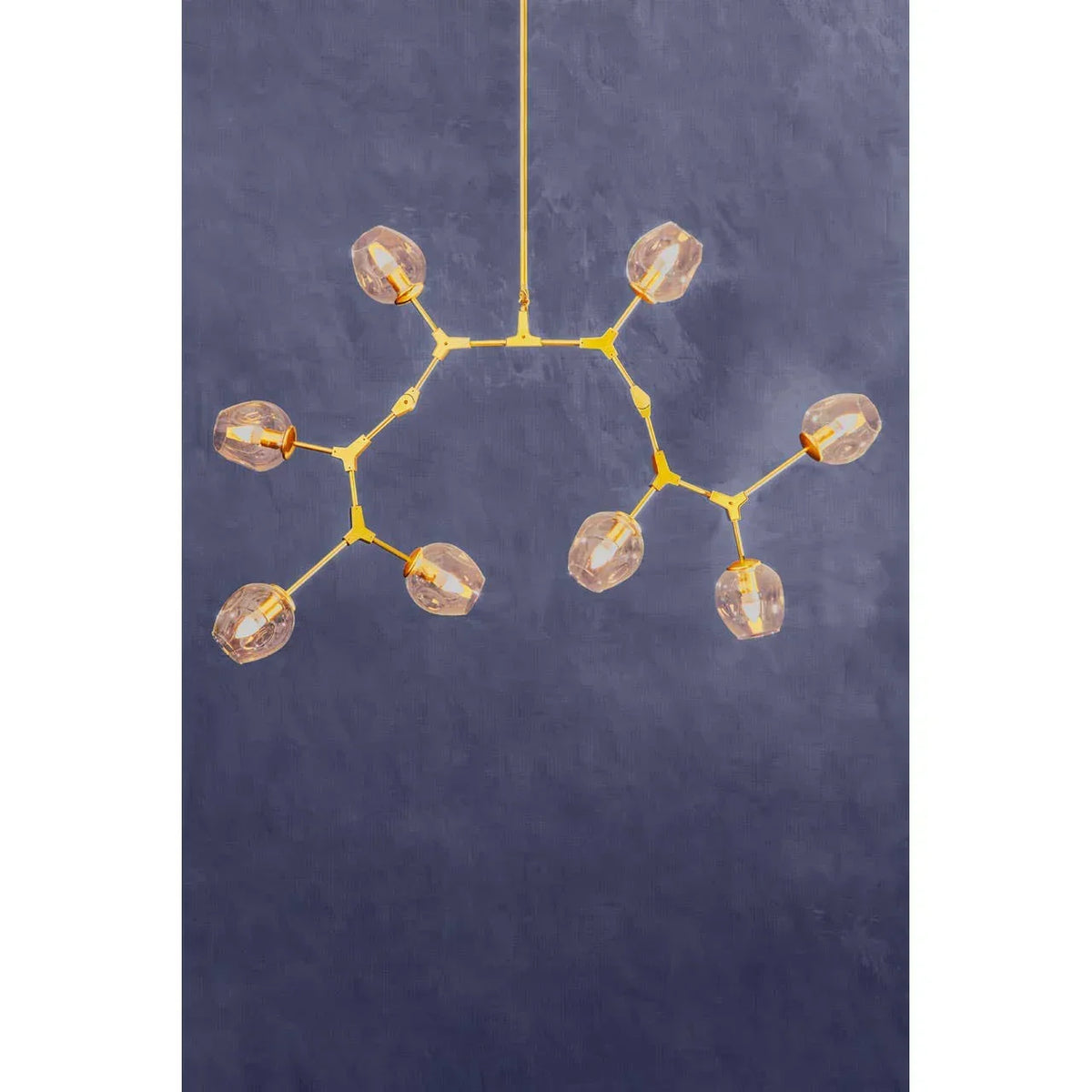 Modern gold ceiling light fixture with eight glass globes against a blue wall