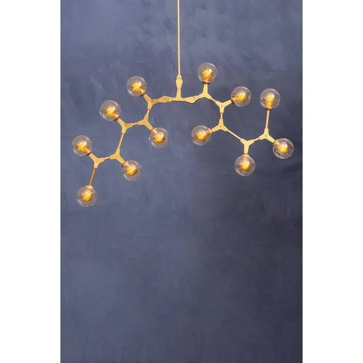 Modern gold chandelier with glass globe lights against a blue wall