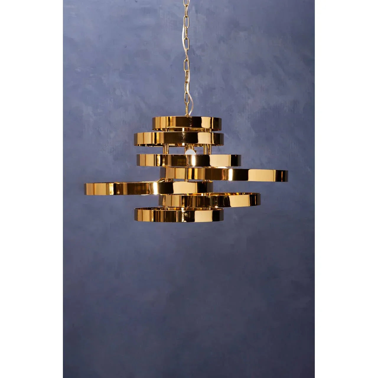 Modern gold pendant light with layered metal rings hanging against blue wall