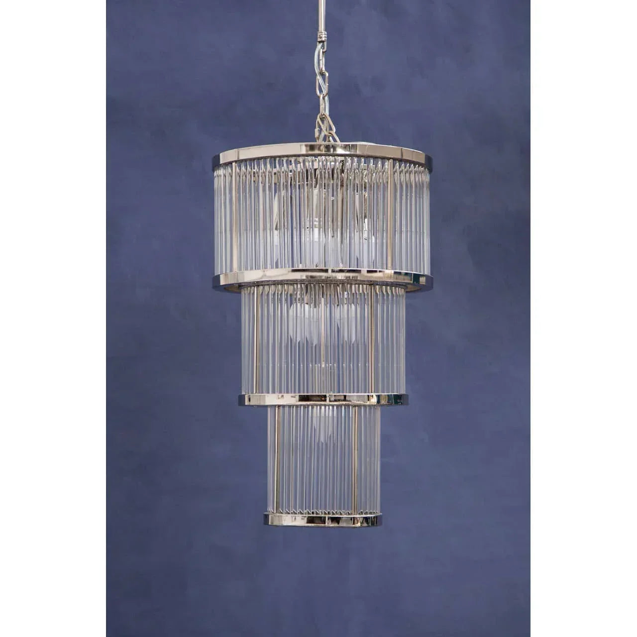 Modern tiered glass pendant light with chrome frame against blue wall background