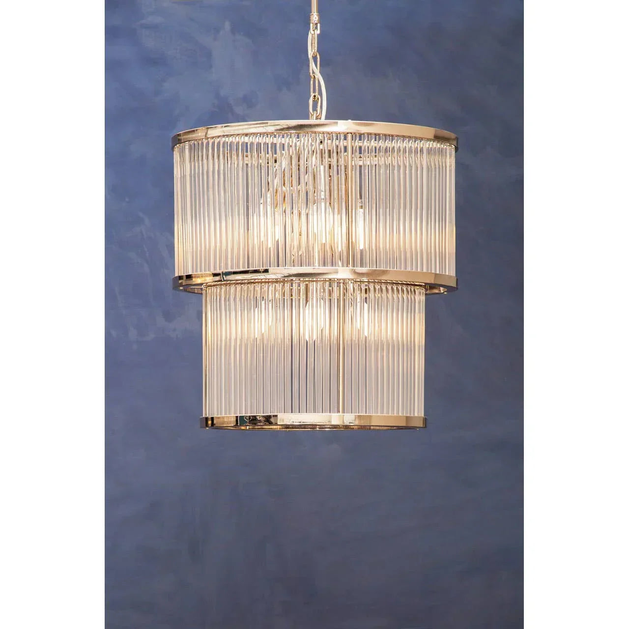 Modern glass chandelier with gold frame and tiered design against blue wall background