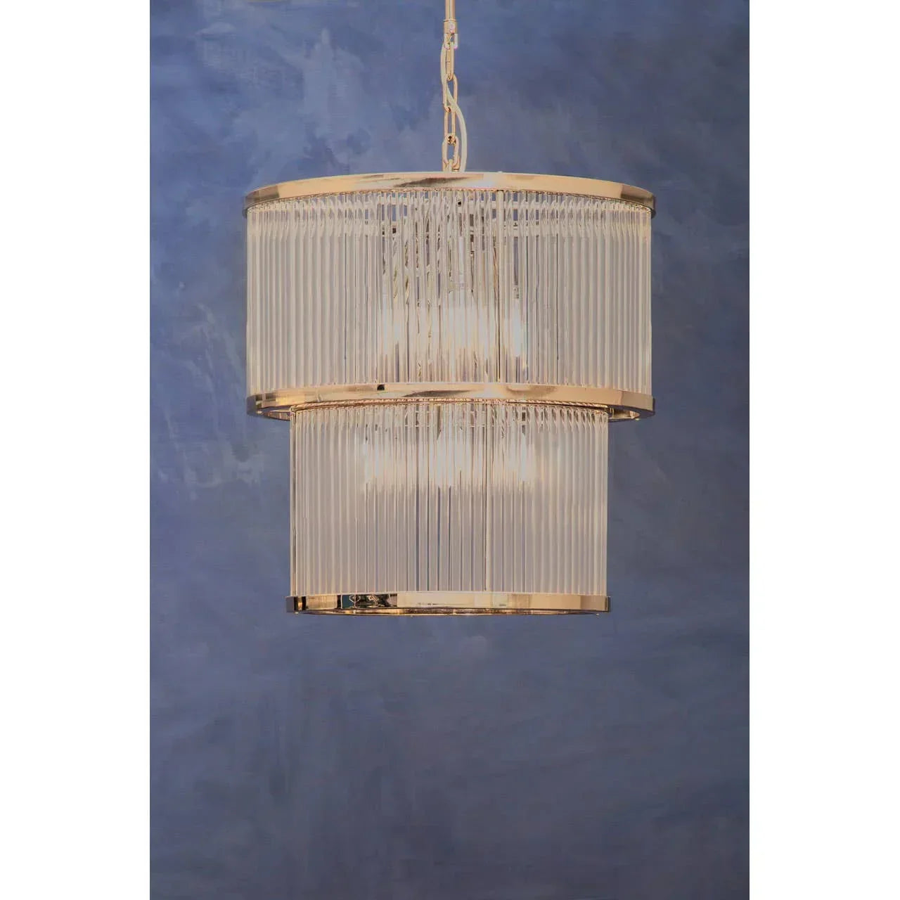 Gold and glass pendant ceiling light fixture with tiered design against blue wall