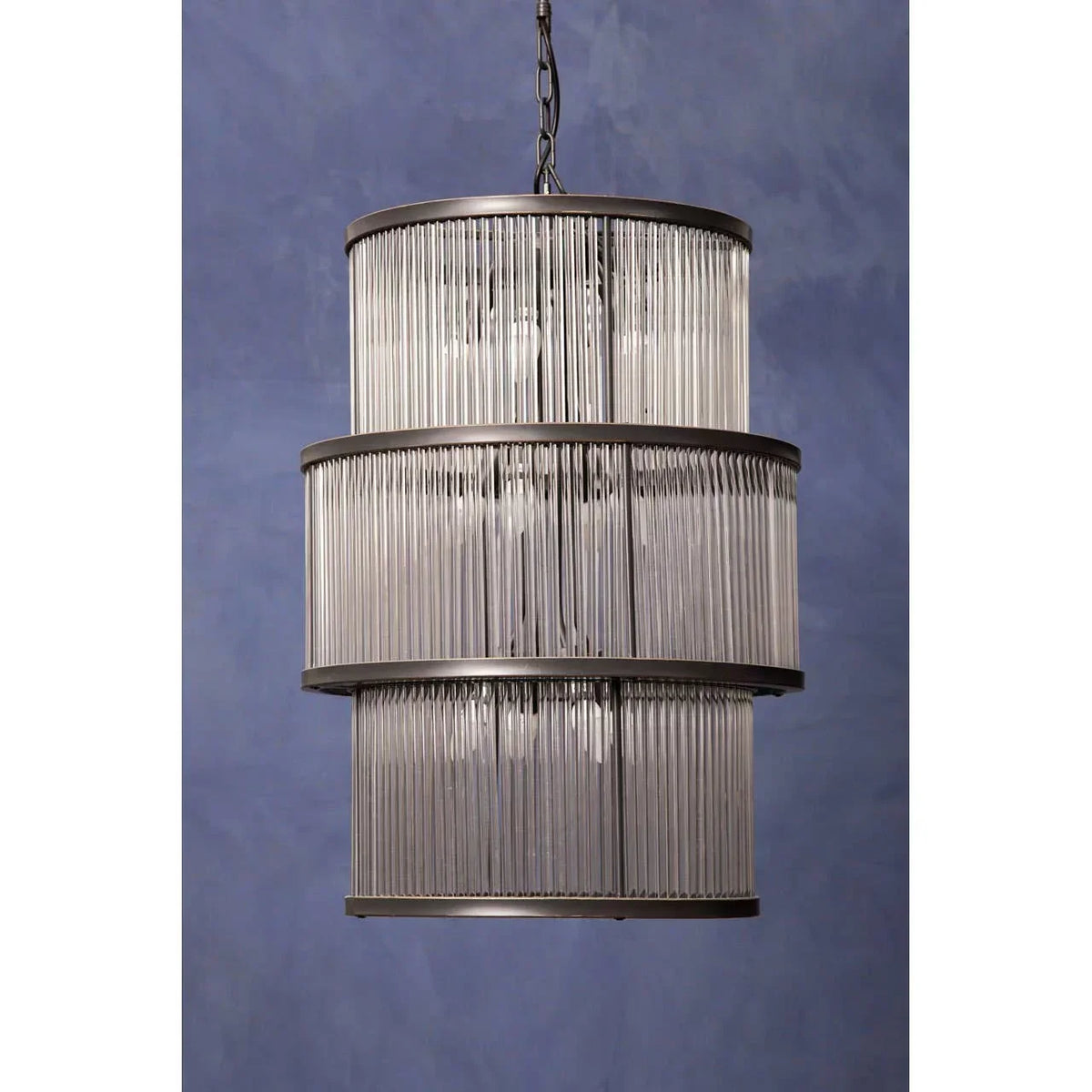 Three-tier glass rod chandelier with chrome frame against blue background