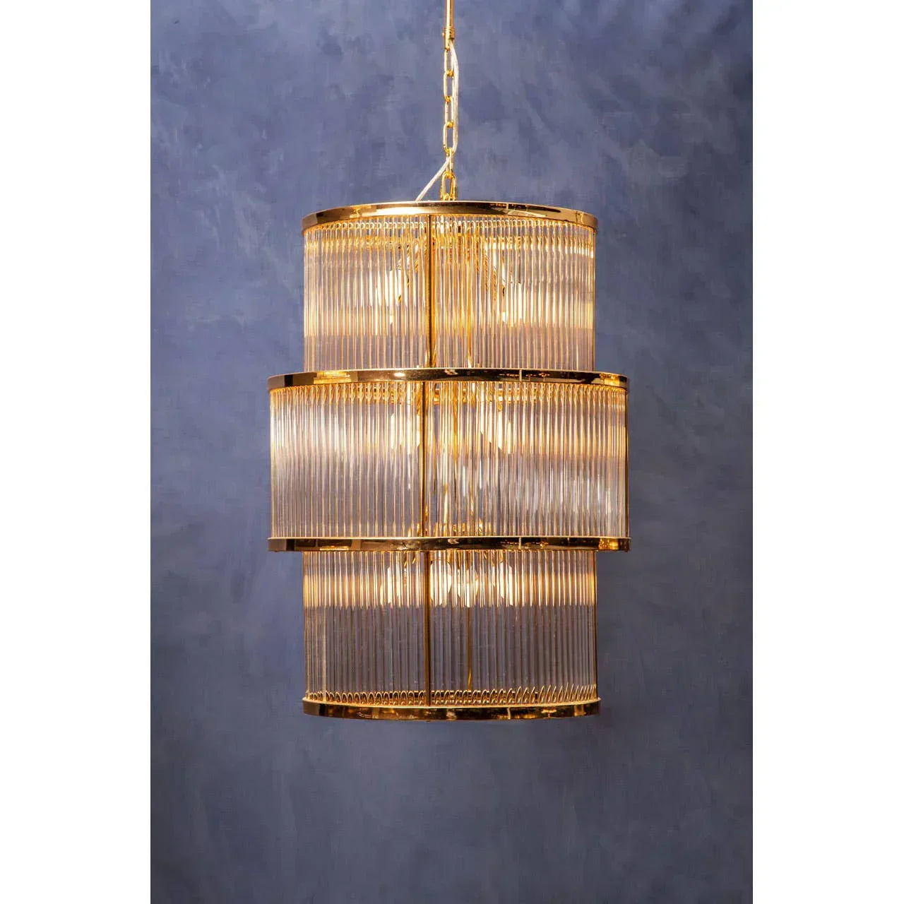 Gold and glass tiered chandelier pendant light against blue wall