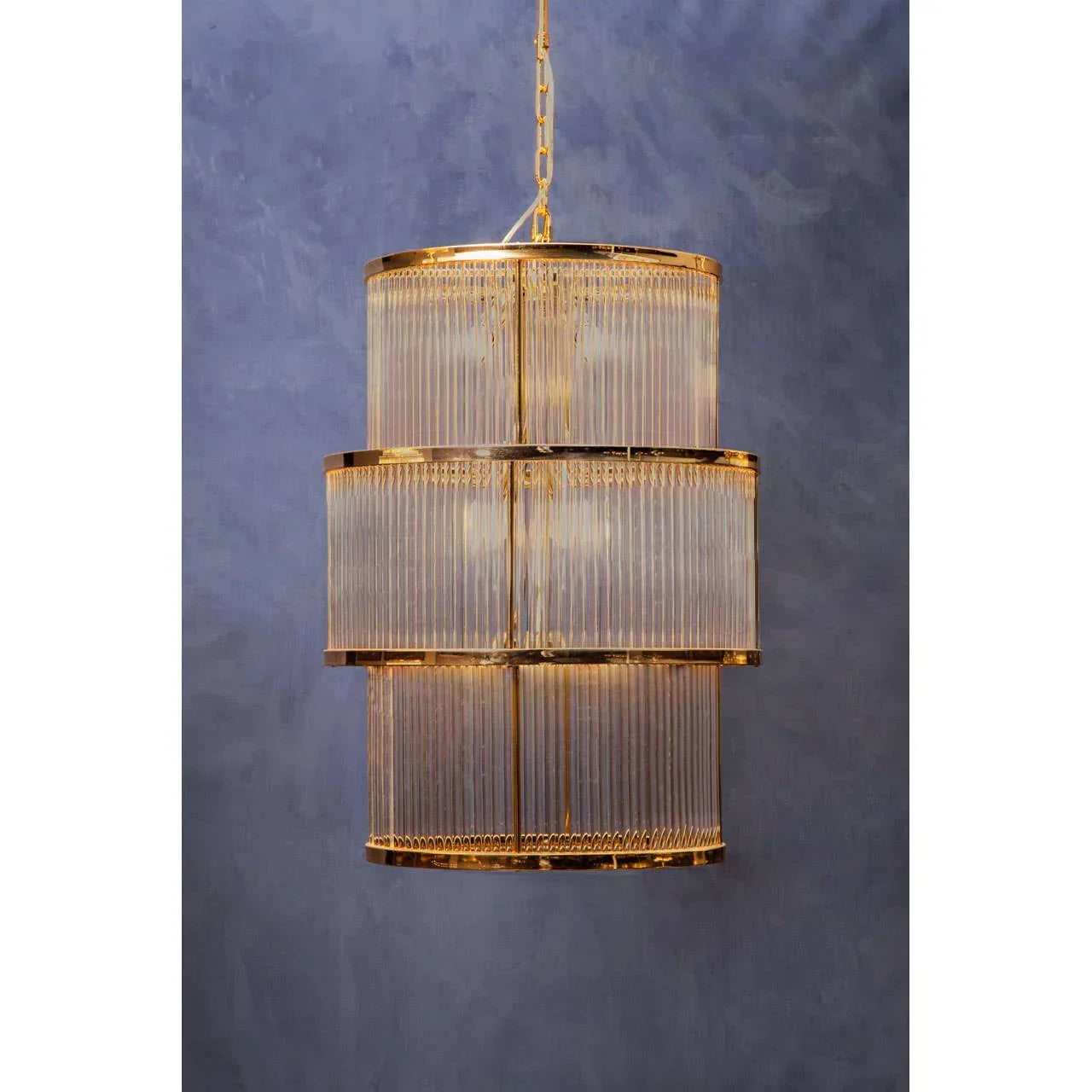 Gold tiered crystal chandelier with glass rods against a grey wall