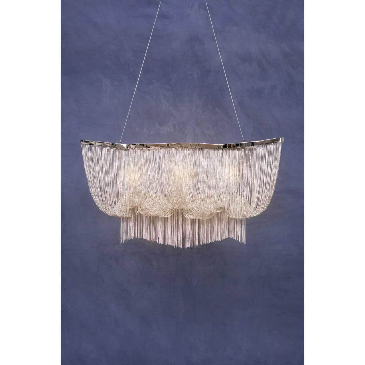 Modern chandelier with cascading silver chain design against blue wall
