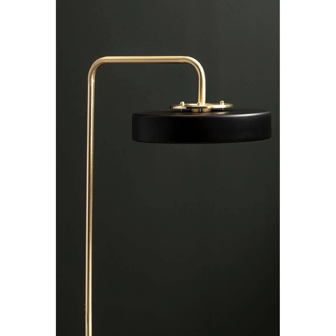 Modern floor lamp with black shade and gold frame against dark background