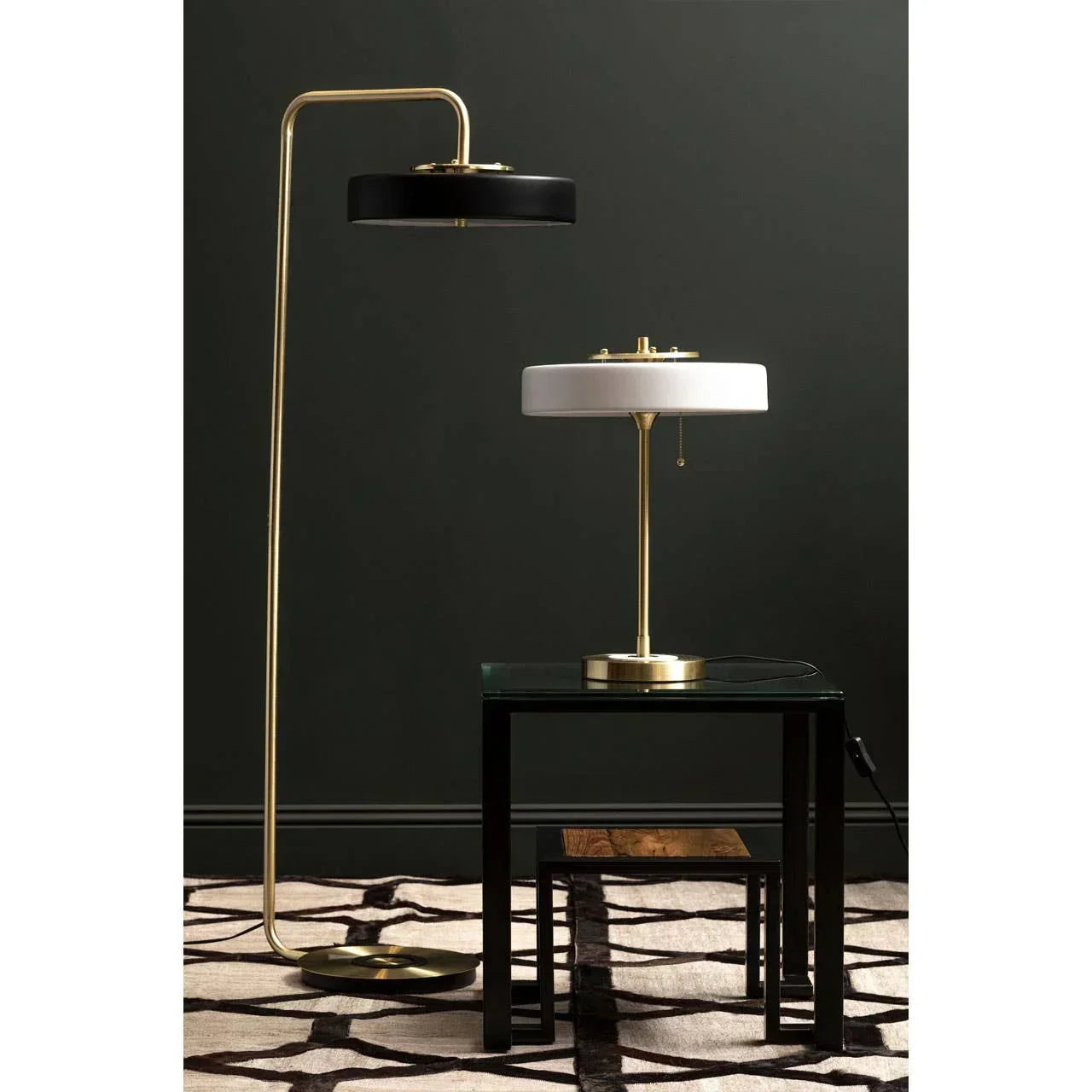 Modern floor lamp with black shade and brass table lamp with white shade on glass side table