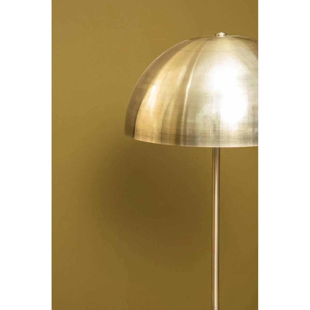 Brushed brass dome floor lamp with slim stand on mustard yellow wall