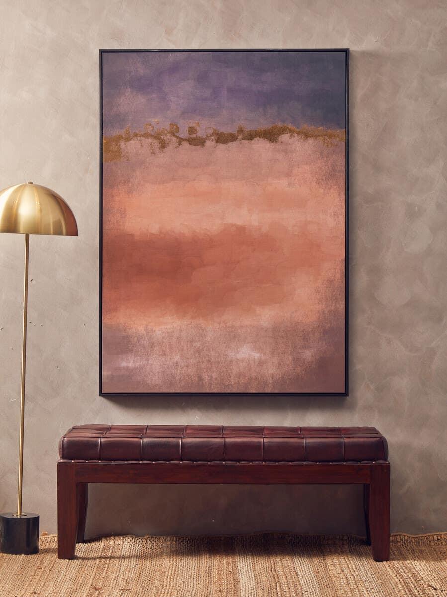 Brown leather bench with tufted seat below abstract wall art and gold floor lamp