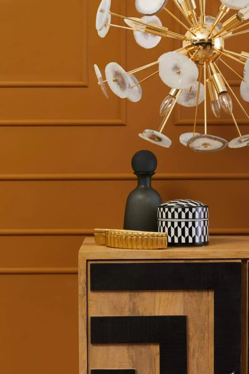 Contemporary sideboard with geometric black pattern, decorative vase, box, and gold accent