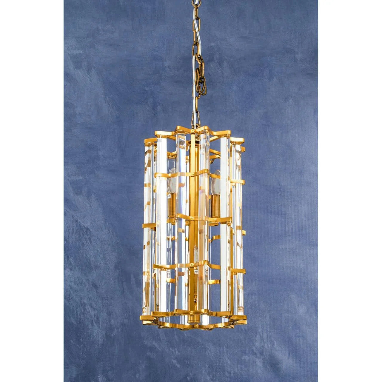 Gold and glass pendant light with geometric frame against blue textured wall
